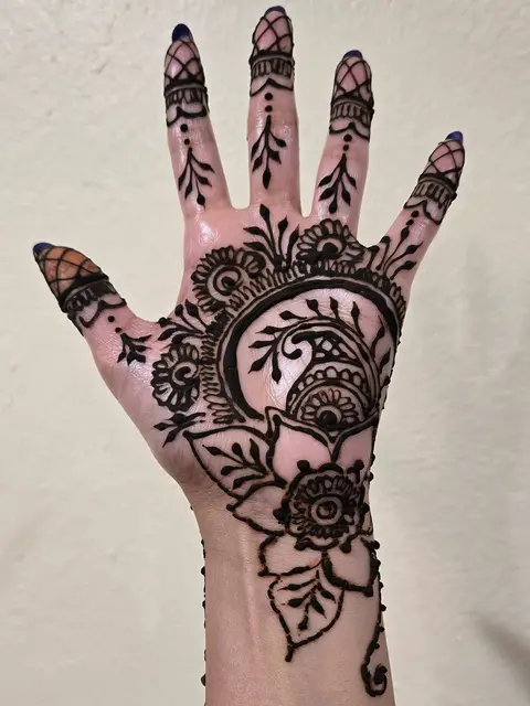 A paisley and flower design on an open palm, with pointed fingertips